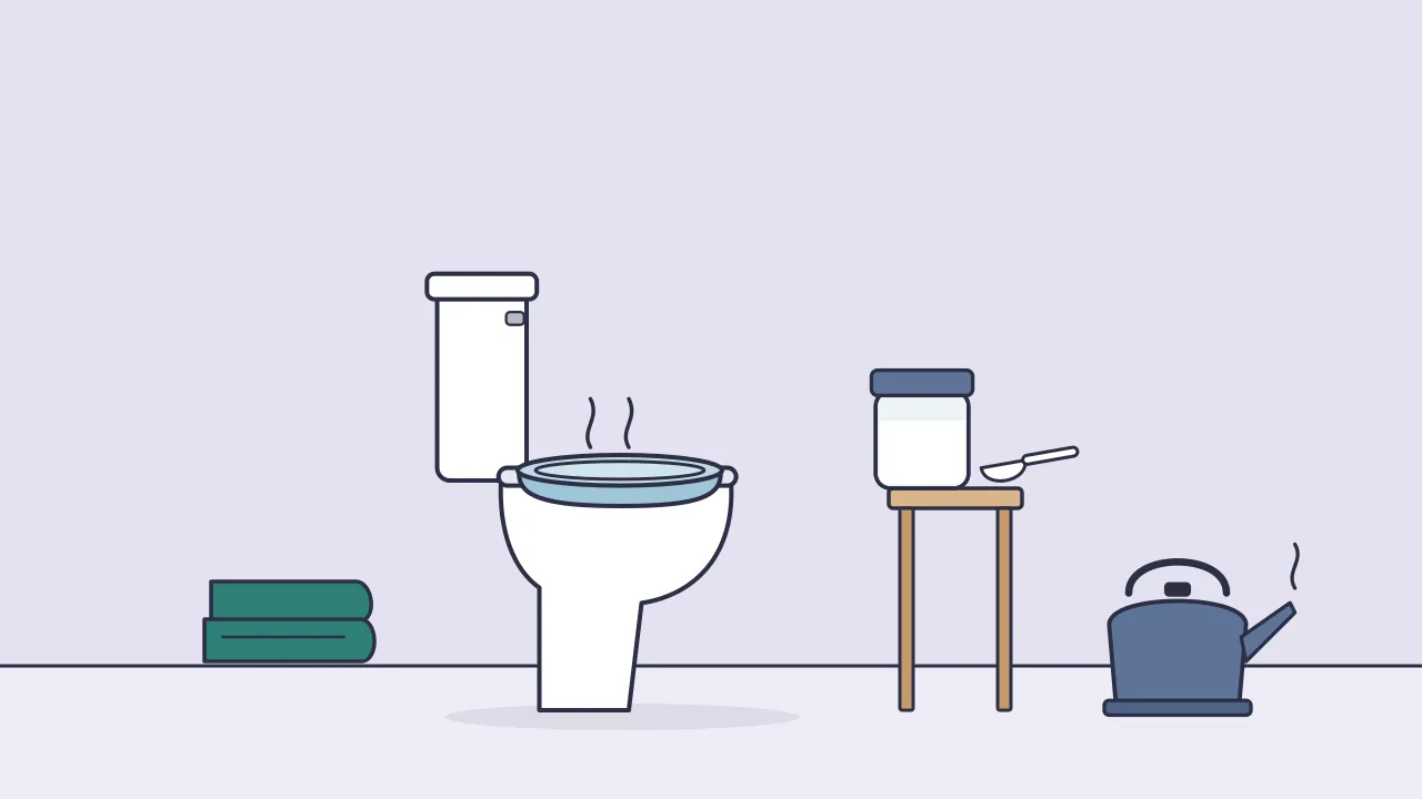 A sitz bath basin on a toilet seat beside a jar of white bath salt with a scoop, a kettle and a folded towel