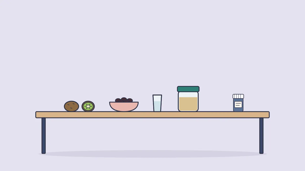 A kitchen table with two kiwifruits, a small bowl of prunes, a glass of water, a jar of fiber powder and a small probiotic bottle off to the side