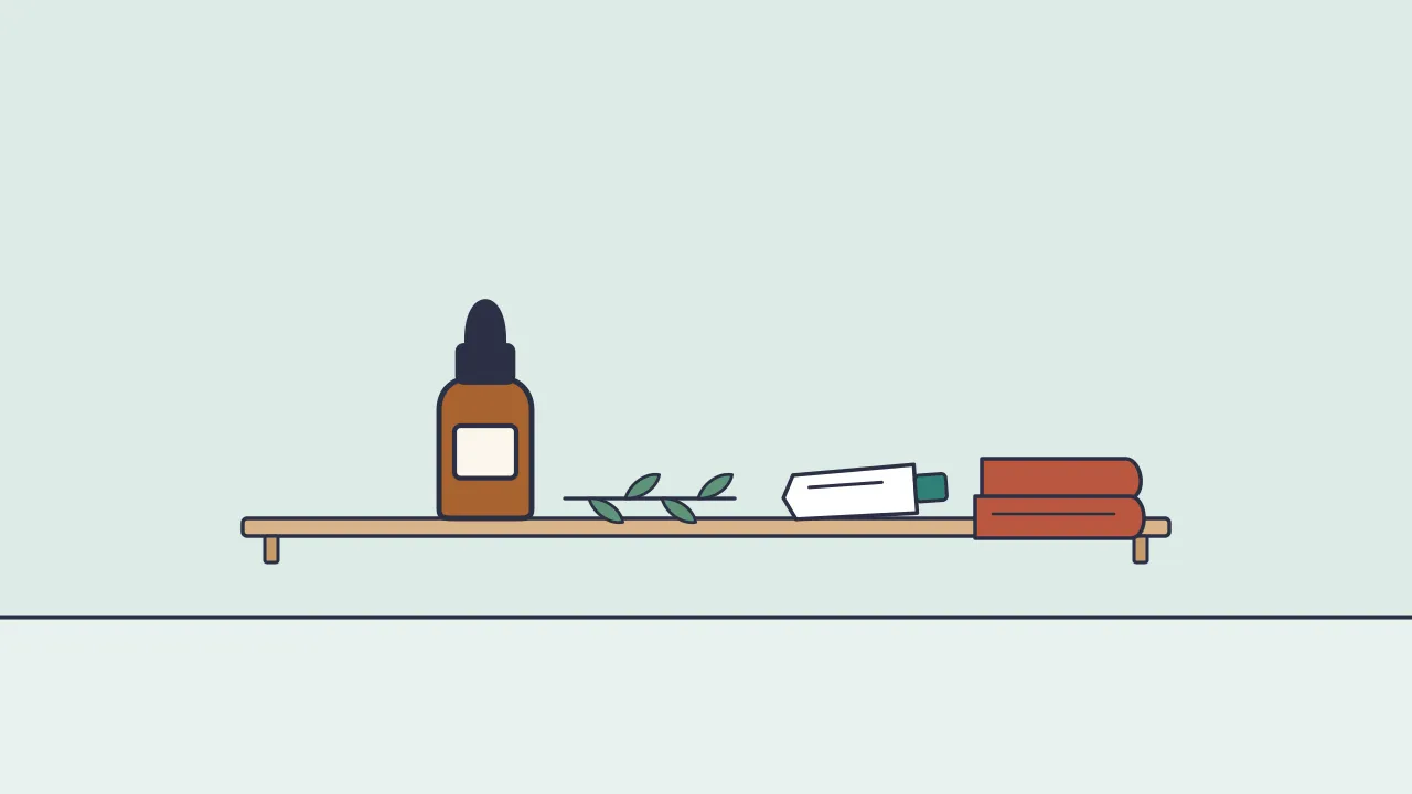 A small brown dropper bottle beside a sprig of narrow green leaves, a tube of gel and a folded towel on a bathroom shelf